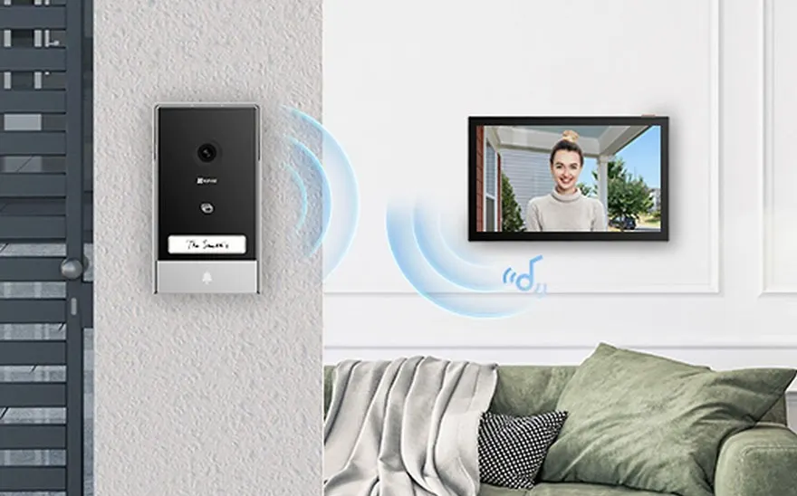 Un système de sonnette vidéo connecté à un écran, avec un canapé en arrière-plan.