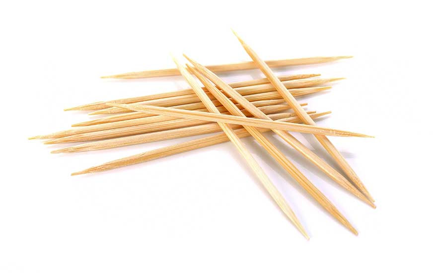 Een stapel houten tandenstokers ligt verspreid op een witte achtergrond.