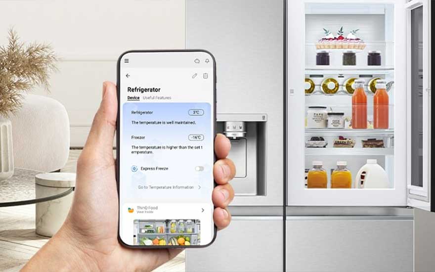 Een hand houdt een smartphone vast met een koelkast-app, naast een witte koelkast gevuld met eten en drinken.