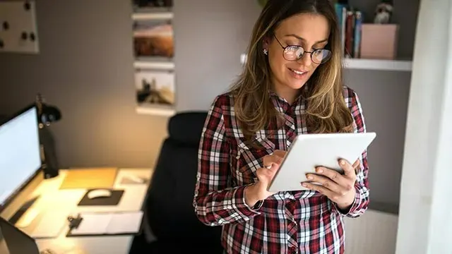 Bureau avec ordinateur, chaise et tablette. La tablette est blanche. La chemise est à carreaux rouge et blanc.
