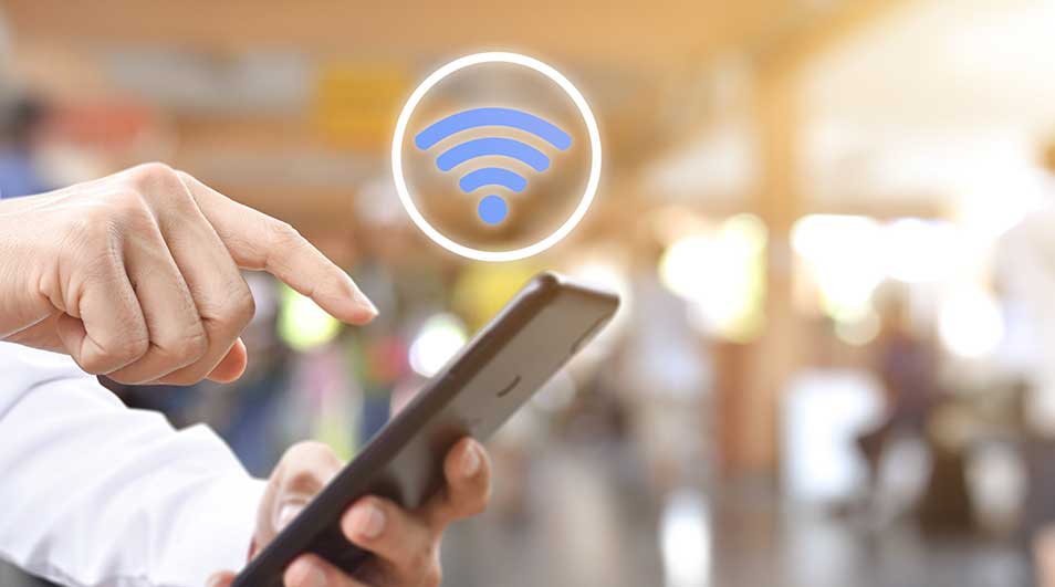 Hand tikt zwarte smartphone aan met blauw wifi-symbool. Vage achtergrond.