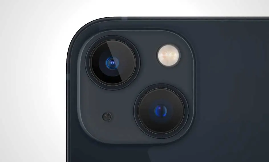 Gros plan du coin d'un smartphone bleu marine montrant deux objectifs de caméra circulaires et un flash sur un fond blanc uni.