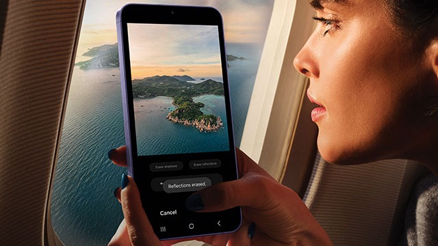 A phone displays an island view. Outside the plane window, the same island and ocean stretch.