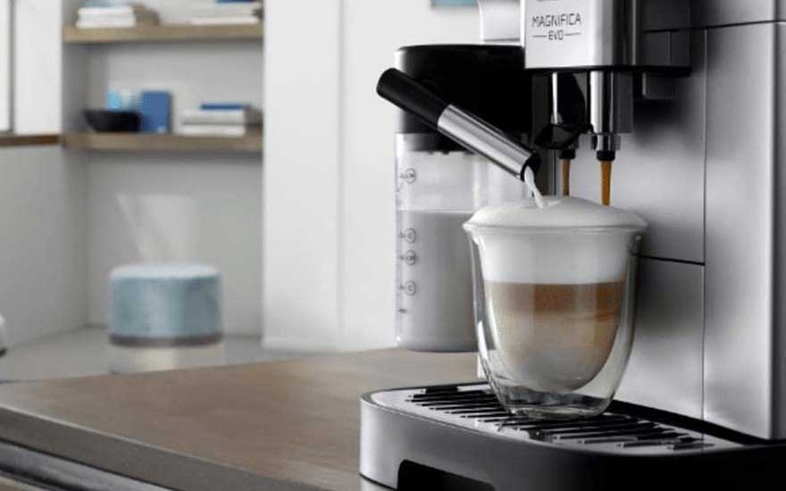 Magnifica Evo vult een glas met gelaagde koffie en melk, terwijl de actieve opschuimer een zijdezachte melkschuimkraag maakt.