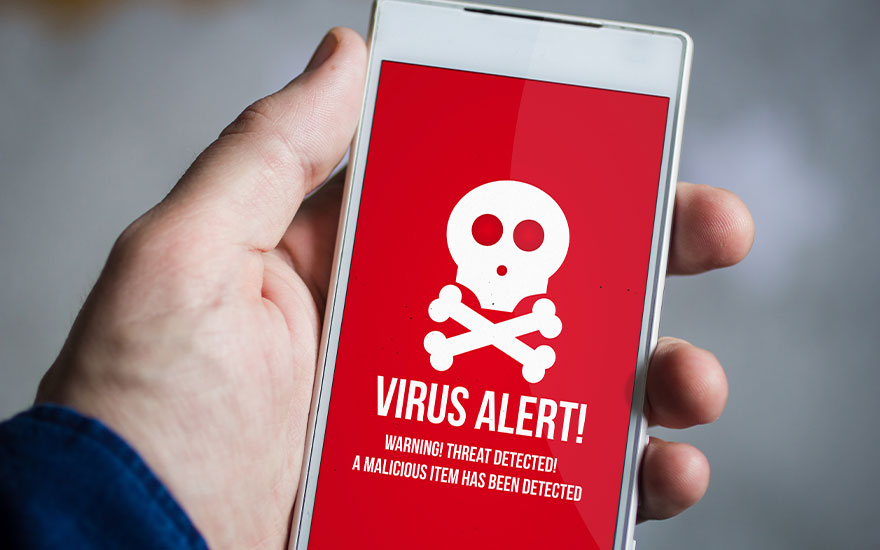 Een hand houdt een witte smartphone vast. Op het rode scherm staat een witte doodskop en de tekst "VIRUS ALERT!".