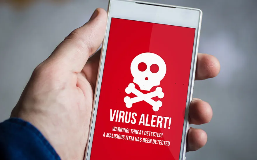 Een hand houdt een witte smartphone vast. Op het rode scherm staat een witte doodskop en de tekst "VIRUS ALERT!".