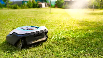 Une tondeuse robot Gardena tond automatiquement la pelouse verte sans intervention humaine.