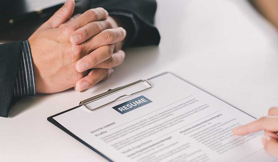 Un CV sur une planche à pince, avec texte et mains. Fond blanc.