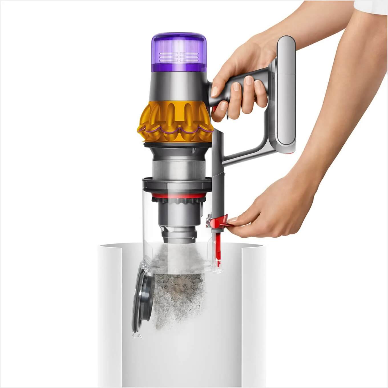 Main tenant un aspirateur Dyson gris, or et violet au-dessus d'une poubelle blanche, vidant la poussière.
