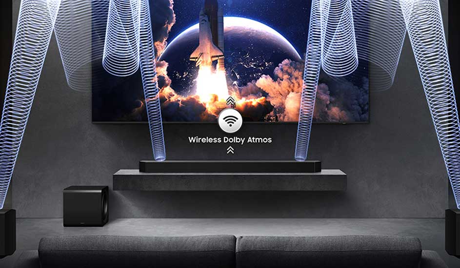 Een Samsung televisie met soundbar en subwoofer toont een raketlancering, met draadloze Dolby Atmos-golven die het surroundgeluid visualiseren.