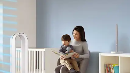 Une pièce avec un lit d'enfant blanc, un ventilateur blanc et une étagère blanche contenant des livres colorés.