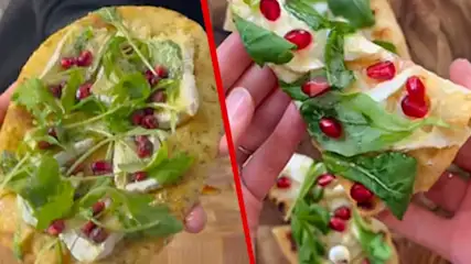 Deux pains plats garnis de fromage, roquette et grenades, présentés dans des mains sur fond neutre.