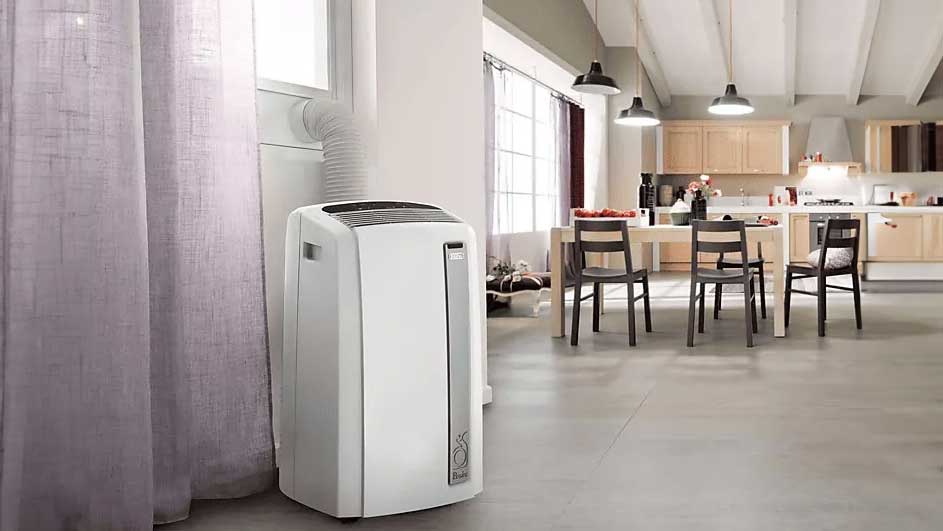 Un climatiseur blanc portable est à côté d'un rideau violet, avec une cuisine en arrière-plan.