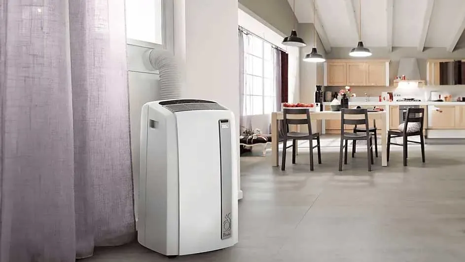 Un climatiseur blanc portable est à côté d'un rideau violet, avec une cuisine en arrière-plan.