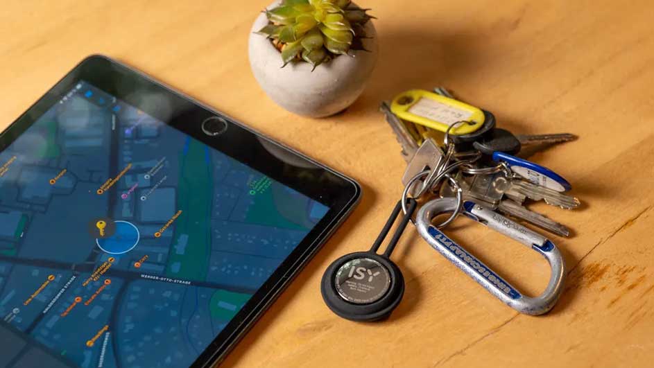 Een tablet met een kaart, sleutels aan een ring en een plant op een houten tafel.