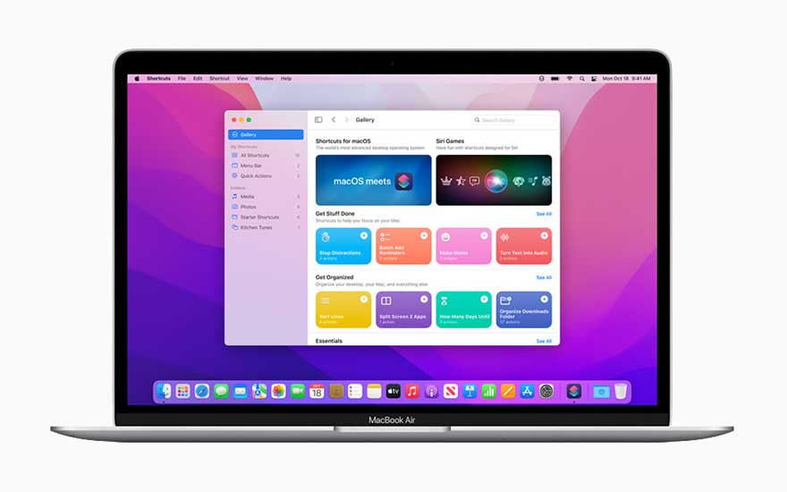 Un MacBook Air gris argenté affiche un écran violet avec des icônes d'applications colorées et une fenêtre d'application ouverte.