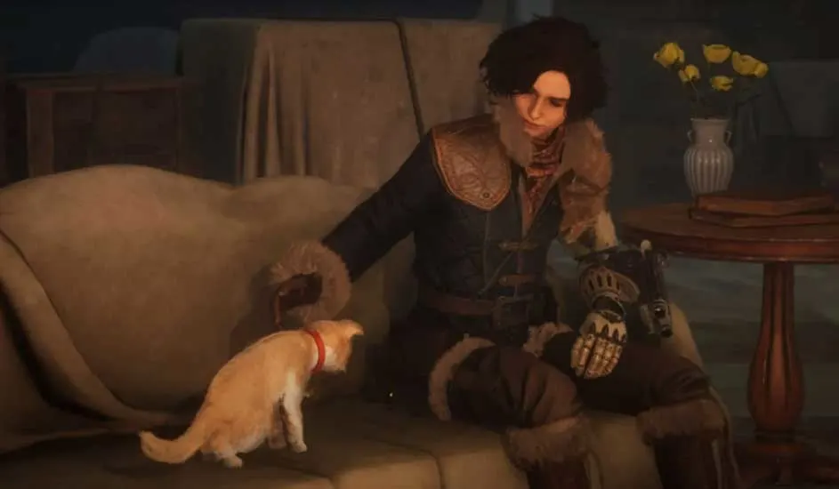 Un chat roux avec un collier rouge se tient près d'un canapé beige. Une personne est assise sur le canapé, portant un vêtement foncé.