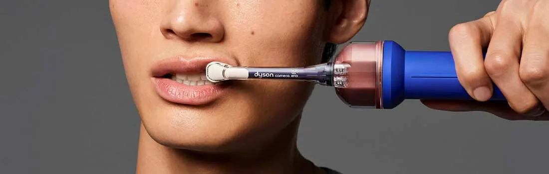 Un gros plan montre une personne faisant glisser une brosse à dents électrique équipée d’une caméra le long de ses dents.