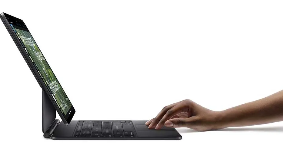 Un ordinateur portable noir est incliné avec un écran affichant une image verte. Une main est au-dessus du clavier.