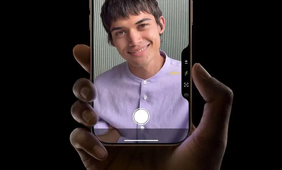 Main tenant un smartphone qui affiche une personne sur un fond rayé.