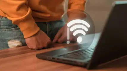 Een laptop op een houten tafel met een wifi-symbool dat een verbindingsprobleem aangeeft.