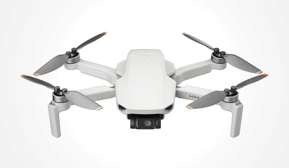 Voici un drone DJI Mini blanc avec quatre hélices et une caméra à l’avant, compact et léger.