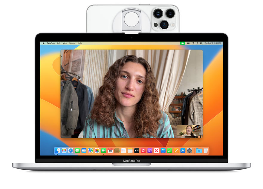 Un MacBook Pro argenté affiche un appel vidéo sur son écran. Un iPhone blanc est fixé au-dessus de l'écran.