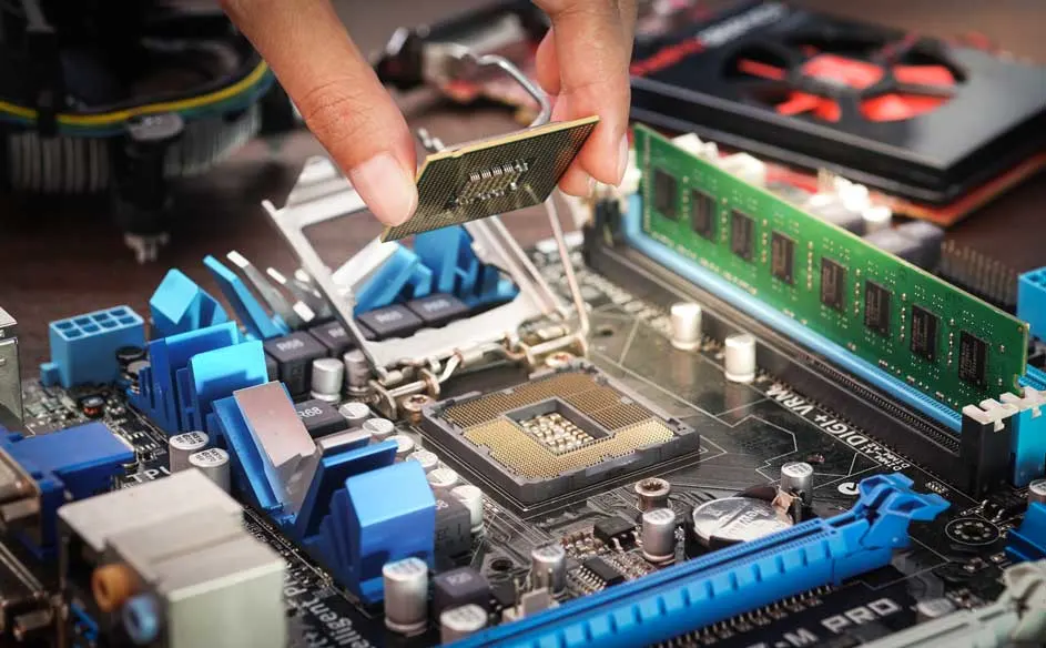 Een hand plaatst een CPU in een blauw moederbord met een groene RAM-module en een zwarte koeler.