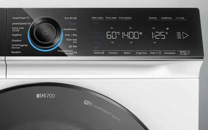 Een witte Siemens iQ700 wasmachine met groot digitaal display toont temperatuur, toerental en programmaduur in een moderne, minimalistische ruimte.