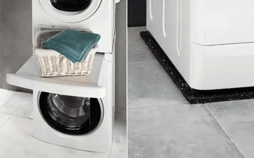 Een wit gestapelde wasmachine en droger met een mand met blauwe handdoeken. De machine staat op een zwarte antislipmat op grijze tegels.