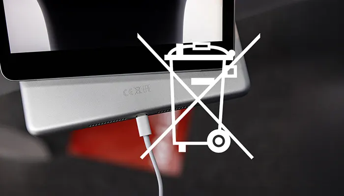 Gros plan d’une tablette avec câble de charge et pictogramme poubelle barrée, ne jette pas avec les déchets ménagers (DEEE).