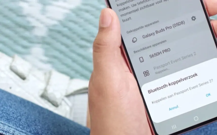 Main tenant un smartphone montrant une demande de connexion Bluetooth pour "Passport Event Series 2?". L'arrière-plan est flou.
