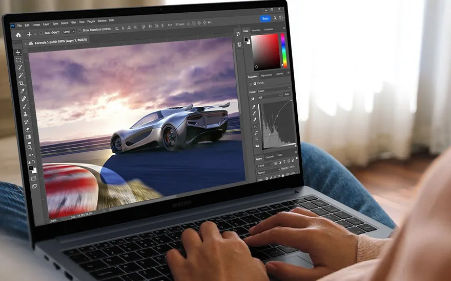 Een laptop toont een bewerkingsprogramma met een afbeelding van een zilverkleurige auto op een racebaan tegen een bewolkte hemel.