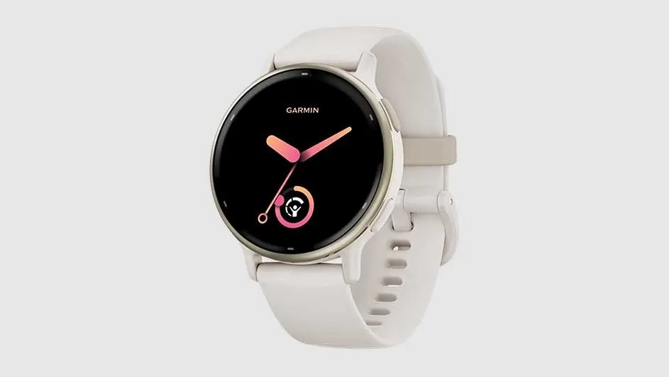 A Garmin watch features a black face with pink hands, surrounded by a light-colored band. The background is a solid, light grey.