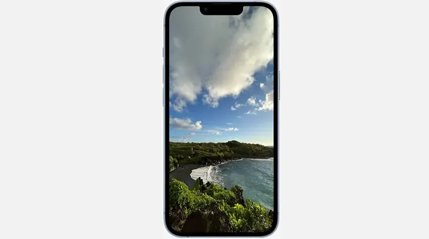 Un smartphone affiche une plage noire, une mer bleue et un ciel nuageux.