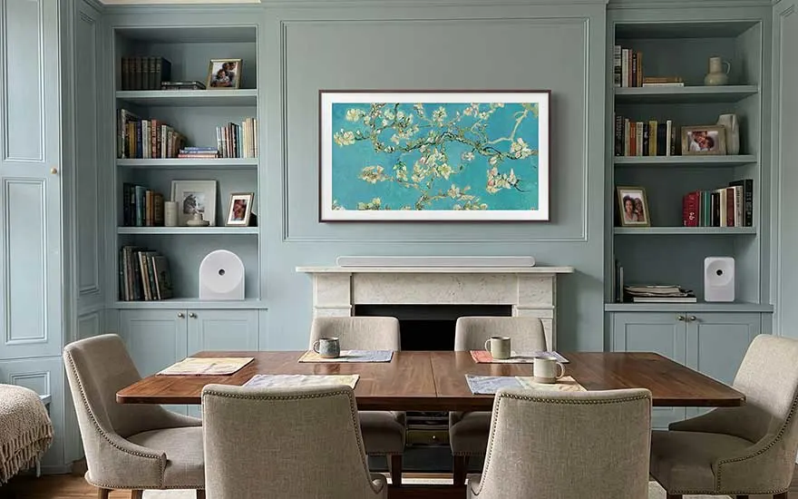 Une élégante salle à manger associe des rangements bleus, une cheminée en marbre, des fauteuils et un écran aux fleurs blanches.