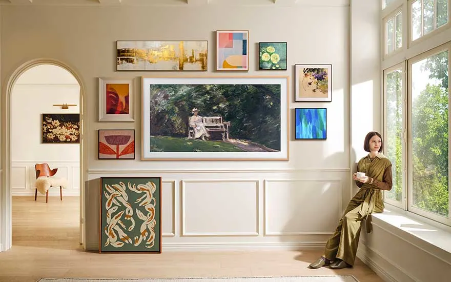 Colourful paintings and patterns are arranged around a large framed artwork on a stairway wall, in a luminous and stylish area.