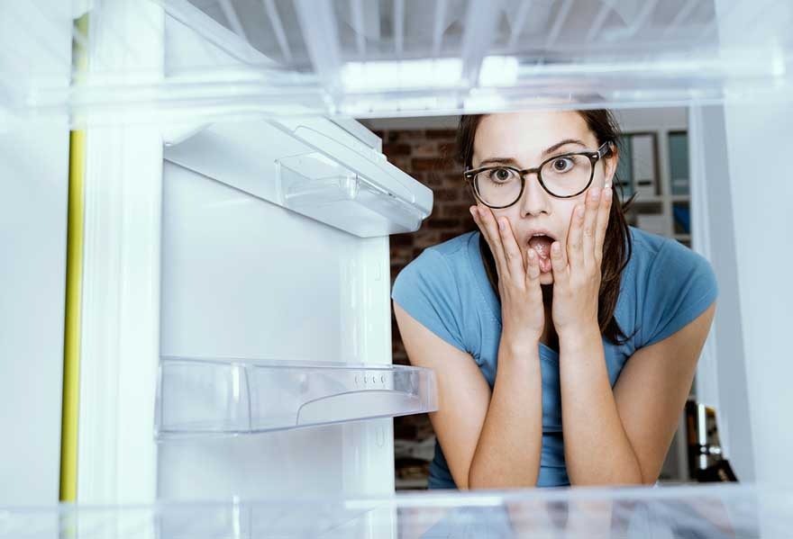 Vue depuis l'intérieur d'un réfrigérateur blanc vide avec des étagères en plastique transparent.