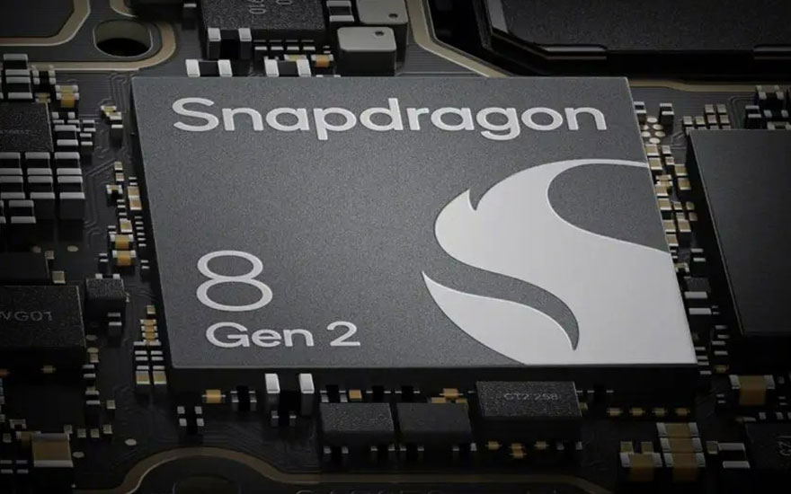Gros plan d'une puce Snapdragon 8 Gen 2 grise sur un circuit imprimé noir avec de petits composants électroniques.