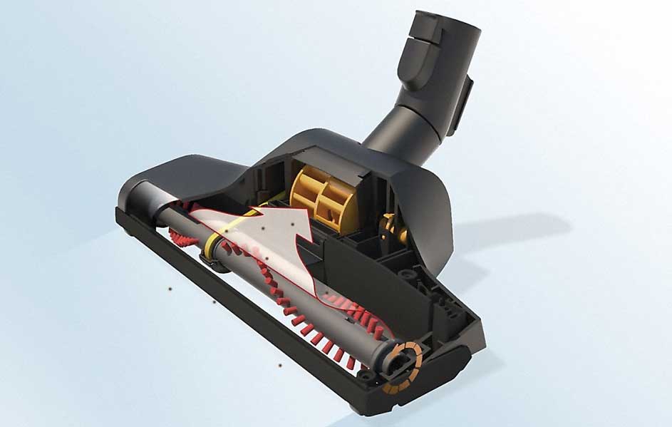 Tête d'aspirateur noire avec une brosse rotative rouge et grise, et une flèche blanche indiquant le flux d'air sur fond bleu clair.