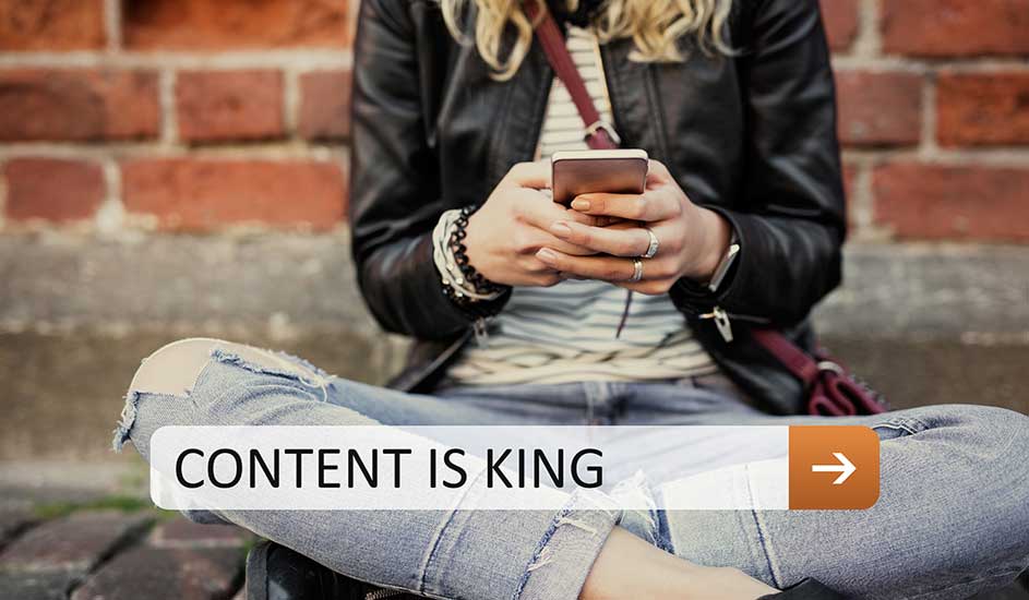 Une personne assise croise les jambes, tenant un téléphone portable devant un mur de briques. Une barre blanche avec le texte "CONTENT IS KING".