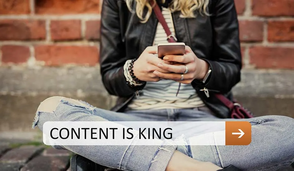 Une personne assise croise les jambes, tenant un téléphone portable devant un mur de briques. Une barre blanche avec le texte "CONTENT IS KING".