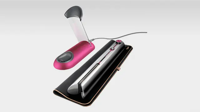 Fer à boucler rose et lisseur argenté sur un tapis noir, le tout sur un fond blanc uni.
