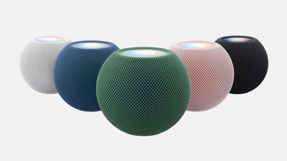 Five round wireless speakers appear against a light background, colored white, blue, green, pink, and black. The green one is in front.