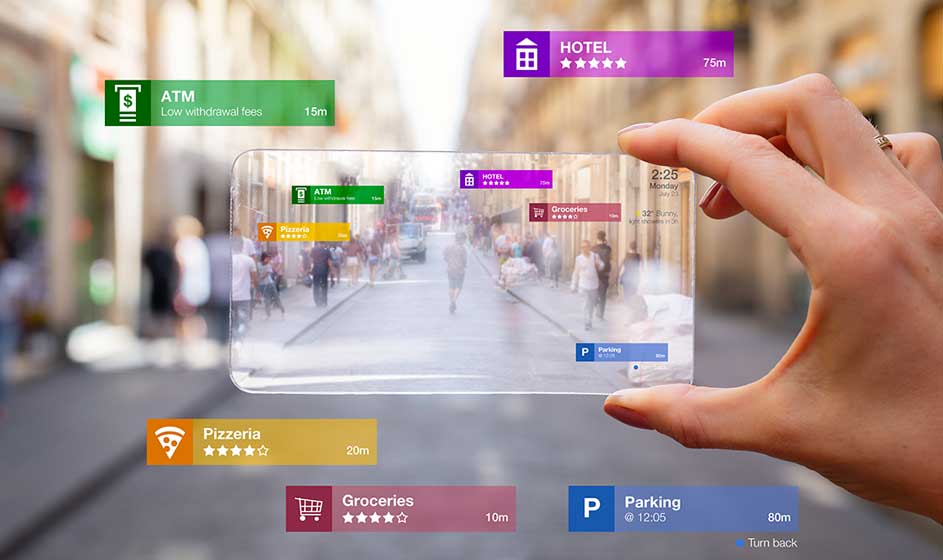 Une main tient un écran transparent au-dessus d’une rue commerçante animée. Des icônes indiquent hôtels, distributeur, pizzeria, magasins et parking.