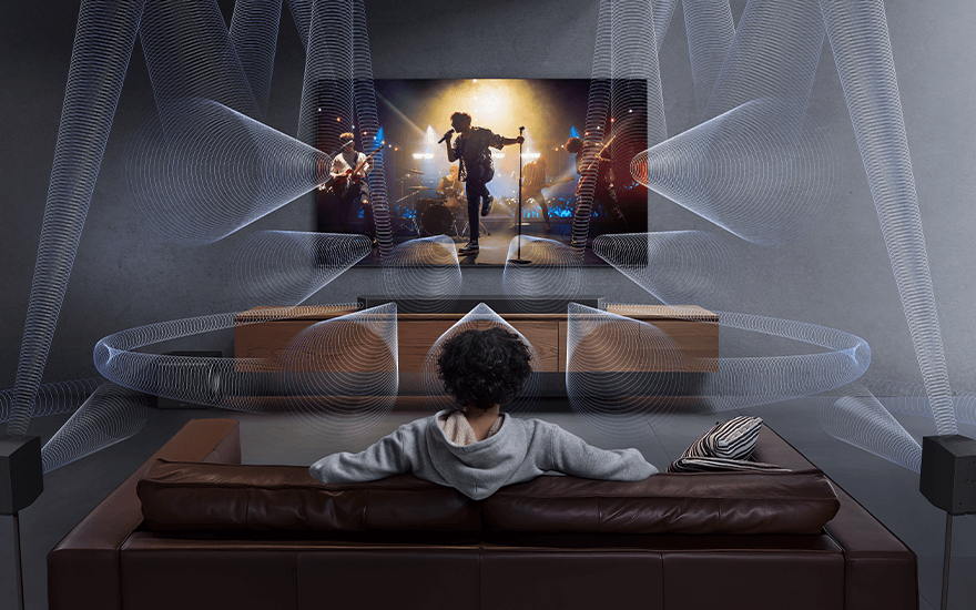 Een woonkamer met een tv waarop een concert te zien is, omgeven door geluidsgolven, met een bruine leren bank.