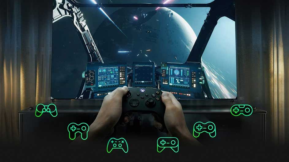 Une personne tient une manette Xbox devant un écran affichant un jeu vidéo de vaisseau spatial, avec des icônes de manette vertes en bas.