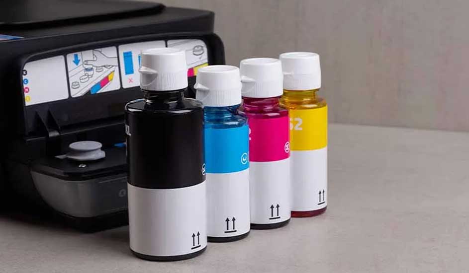 Zicht op een printer met vier inktflessen in zwart, cyaan, magenta en geel, staand op een grijze ondergrond.