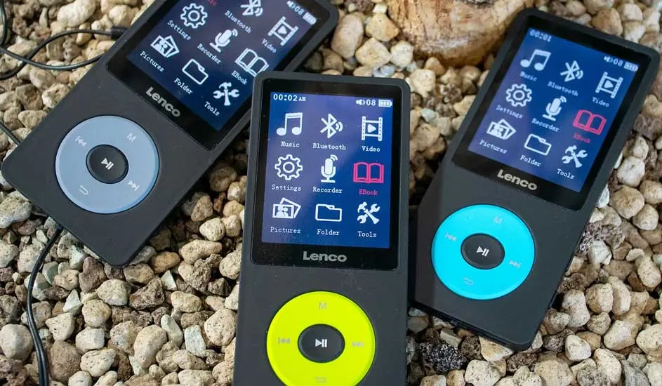 Drie Lenco muziekspelers liggen op een bed van kleine steentjes. De spelers hebben blauwe, gele en grijze bedieningsknoppen.