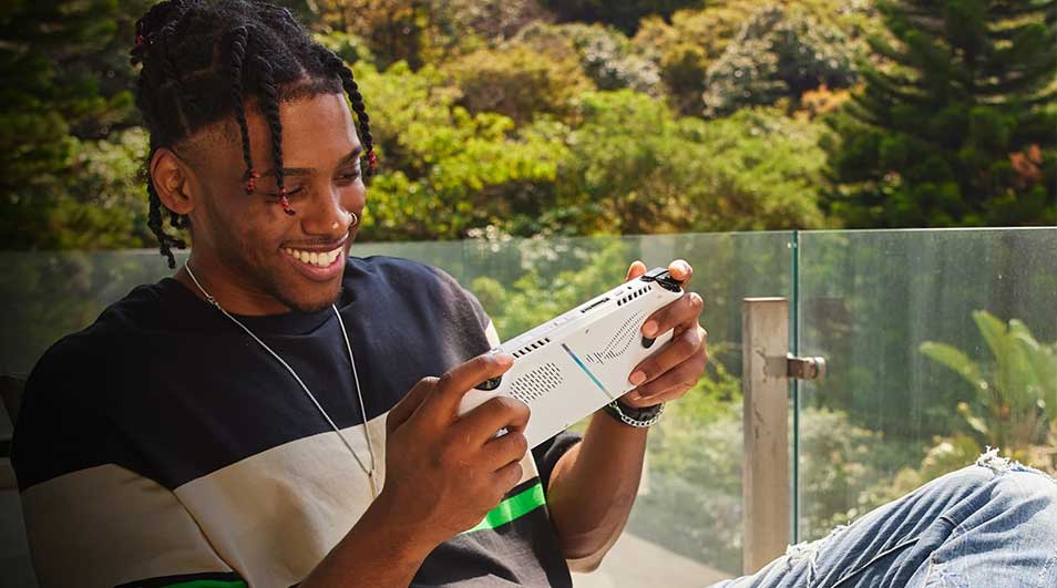 Een wit handheld gamingapparaat wordt gebruikt tegen een achtergrond van groen gebladerte.